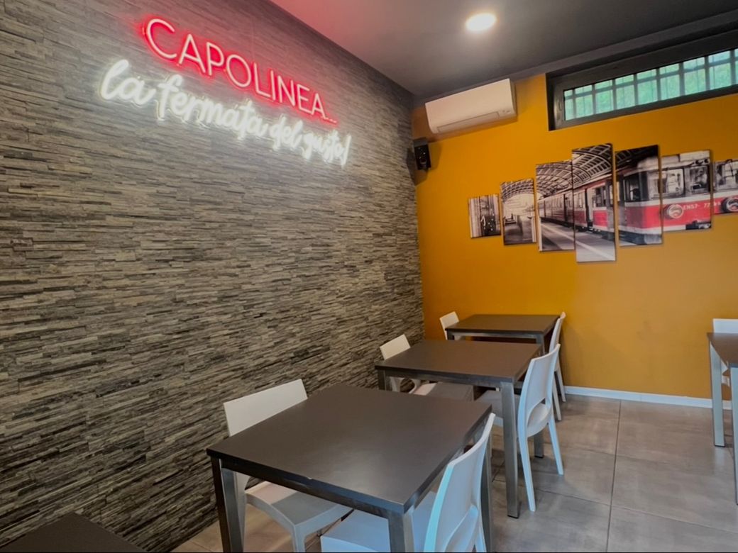 La sala con la parete in pietra, il neon rosso e le foto dei tram sulla parete arancione